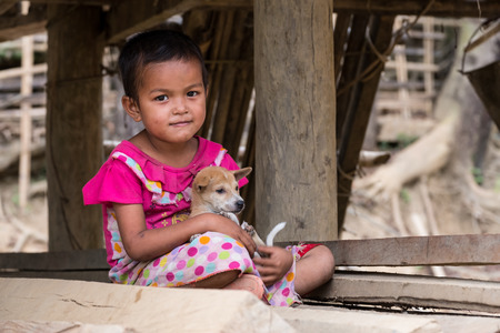 Mrauk U, Rakhine state, Myanmar - Jan 1, 2017: Little girl with her puppy in Chin village.のeditorial素材