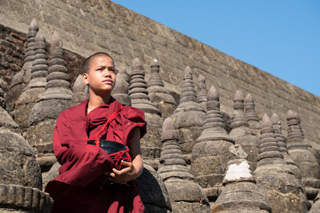 Mrauk-U, Myanma - January 1, 2017: Neophyte (young Buddhist monk) sitting on a little pagoda in Kothaung temple.のeditorial素材