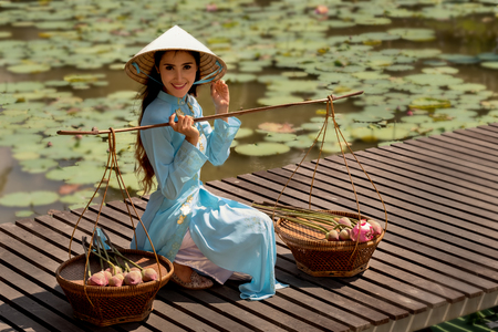 Vietnamese woman with lotus basket on wood bridge over swamp.の写真素材