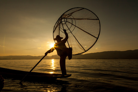 Inle Lake, Myanmar - circa Nov 2013: Burmese man rowing a small boat in Inle Lake. The Inle natives are famous for their unique leg rowing technique.のeditorial素材