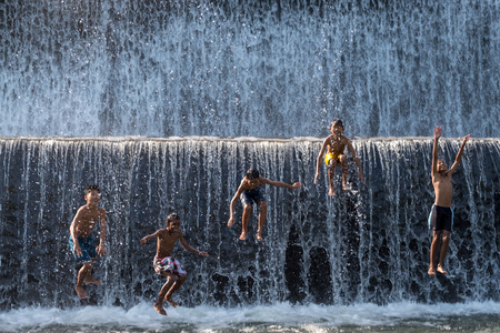 Bali, Indonesia - June 10,2017: Children enjoy playing jump into the water at  Klungkung Dam or Dam Tukad Yeh Unda.のeditorial素材