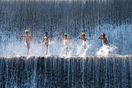 Bali, Indonesia - June 10,2017: Children enjoy playing splash the water at  Klungkung Dam or Dam Tukad Yeh Unda.のeditorial素材
