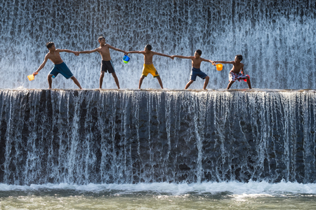 Bali, Indonesia - June 10,2017: Children enjoy playing water at  Klungkung Dam or Dam Tukad Yeh Unda.のeditorial素材
