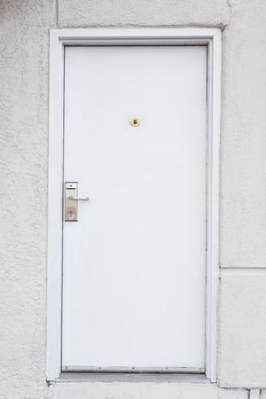 White wall and the closed door outside the buildingの写真素材