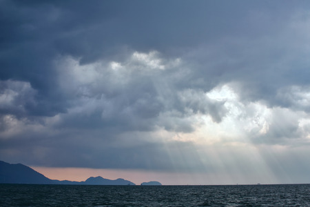View of thunderstorm clouds with ray light above the seaの写真素材