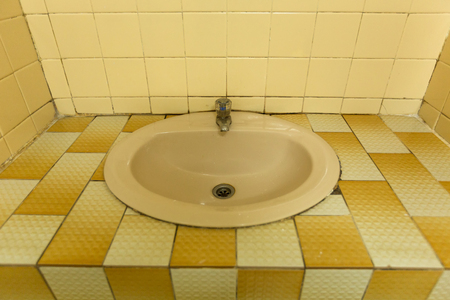 Old wash basin with old faucet and square tile counter in motel bathroomの写真素材