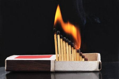 Burning matches in a box on a black background.