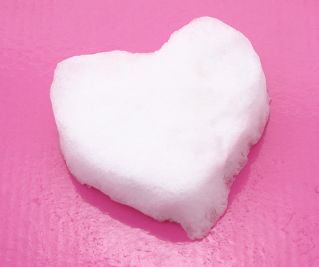 Heart made of snow on a pink background.の写真素材