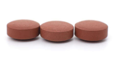 Three brown pills isolated on a white background.の写真素材