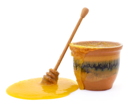 Pot of honey and a spoon isolated on a white background.の写真素材