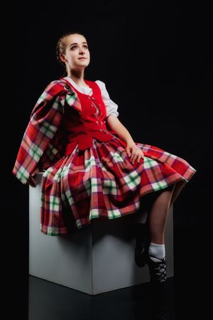 The girl in a kilt sitting on a white cubeの写真素材