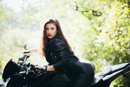 Biker sexy woman sitting on motorcycle. Outdoor lifestyle portraitの写真素材