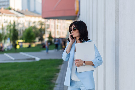 young beautiful, business woman in a hurry to meet with a laptop and a thermal cup in her hands