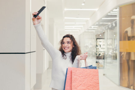Beautiful brunette girl with curly hair. In a modern clothing store, walks through the supermarket,...