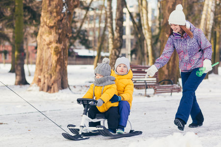 Happy family walking in winter park together, two adult man and woman and two children