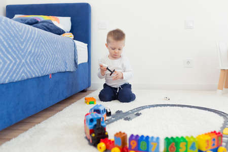 Two little brothers have fun in their nursery, play constructor and trainの写真素材