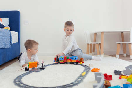 Two little brothers have fun in their nursery, play constructor and trainの写真素材