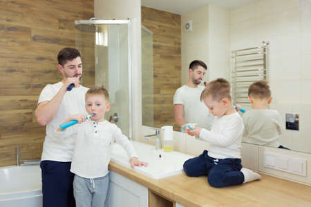 Father and young son brush their teeth in the morning, have fun togetherの写真素材