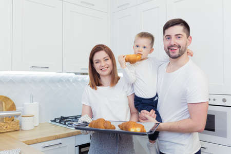 Young happy family with two young sons preparing breakfast together in their kitchenの写真素材