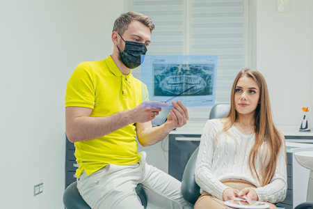 The dentist shows a photo of an X-ray of the patient's teeth in a modern dental clinic. Explains and...