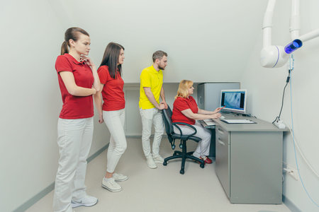 Medical dentist team in dental office discuss and examining x-ray image. looking at computer Desktop...