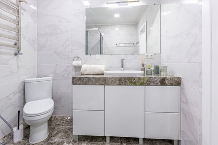 Interior of a modern bathroom with shower, in a small apartment, with white marble tiles