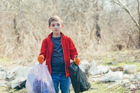 A young teenager collects garbage bags in the woods, a volunteer looks at the camera, and is...