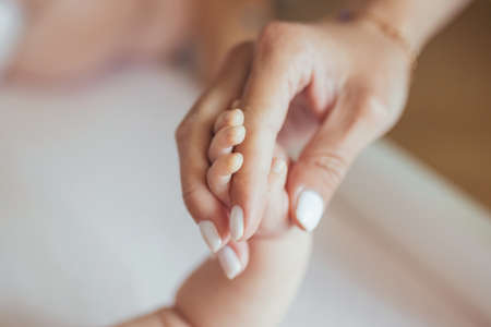 Close-up photo of a newborn baby holding her mother's finger, a woman and a babyの写真素材