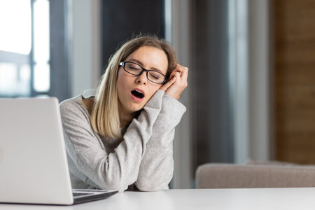 exhausted woman at work yawns from painful sensations caused by wrong posture, sedentary work, long...