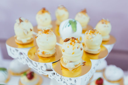 Candy bar. White festive table with deserts, strawberry tartlet and cupcakes. Wedding. Reception...