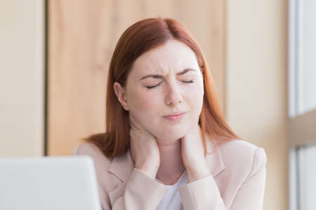 Close-up photo of a red haired business woman with a severe toothache and a headache at the computer, overwork, stress and depressionの写真素材