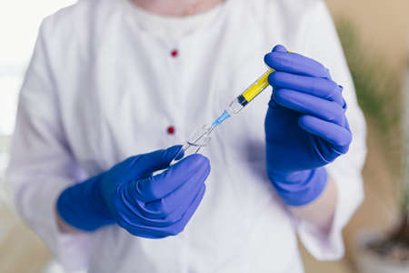 woman's hands dial the vaccine into a syringe, close-up photoの写真素材