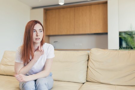Young woman alone at home with a panic attack shortness of breath, trembling, numbness, loss of...