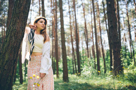 Young beautiful hippie woman walks in the summer forest laughs dances and enjoys life and natureの写真素材