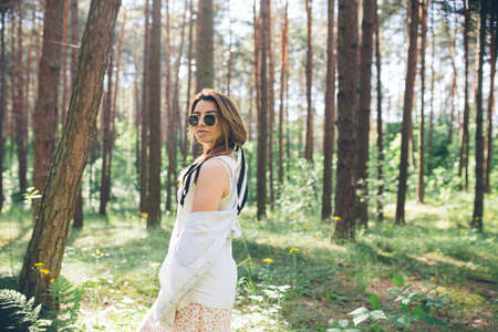 Young beautiful hippie woman walks in the summer forest laughs dances and enjoys life and natureの写真素材
