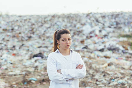 Angry woman standing in a landfill, dissatisfied with the scale of environmental pollution looking into the cameraの写真素材
