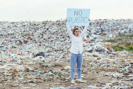 Woman at landfill volunteer holding a poster save the earthの写真素材