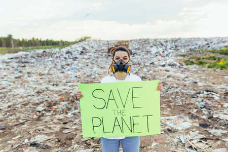 Woman at landfill volunteer holding a poster save the earthの写真素材