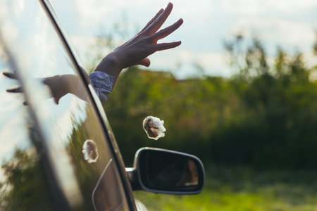 woman throws garbage out the car windowの写真素材