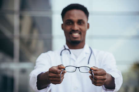 African ophthalmologist doctor offers glasses looking into the cameraの写真素材