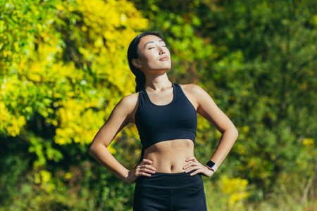 Young beautiful asian female athlete in black sports suit leggings and t-shirt, resting after...