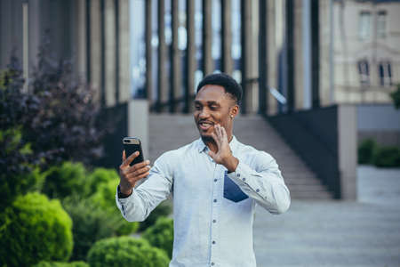 Young african american freelancer talking on video call near office cheerful smiling manの写真素材