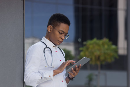 The doctor near the clinic holds a tablet computer, reads the news African-American seriously...