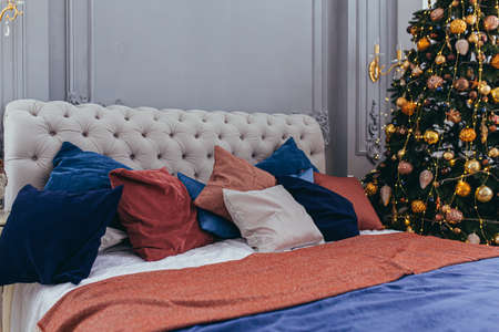 Festive large bed in a hotel room with a decorated Christmas treeの写真素材