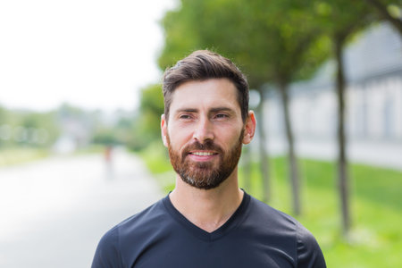 Close up portrait young happy bearded man standing in nature between forest trees relaxes, breathes...