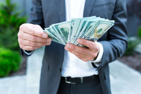 Happy successful Caucasian bearded businessman counts, waves, throws, show off, flaunt cash money background a modern office building looking at camera Celebrate Winner success in betting stock marketの写真素材