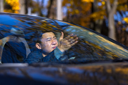 Furious angry asian man standing in a traffic jam beeps and hurries. Sitting in the car. Irritated...