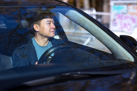 A pensive Asian man is sitting in the car, the driver is waiting and sad