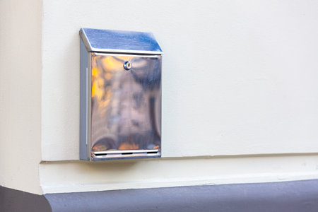 Stainless steel metal mailbox on the white wall of the houseの写真素材