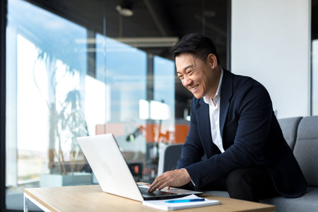 Senior Asian business man working on laptop online, smiling and rejoicing, happy boss business owner...